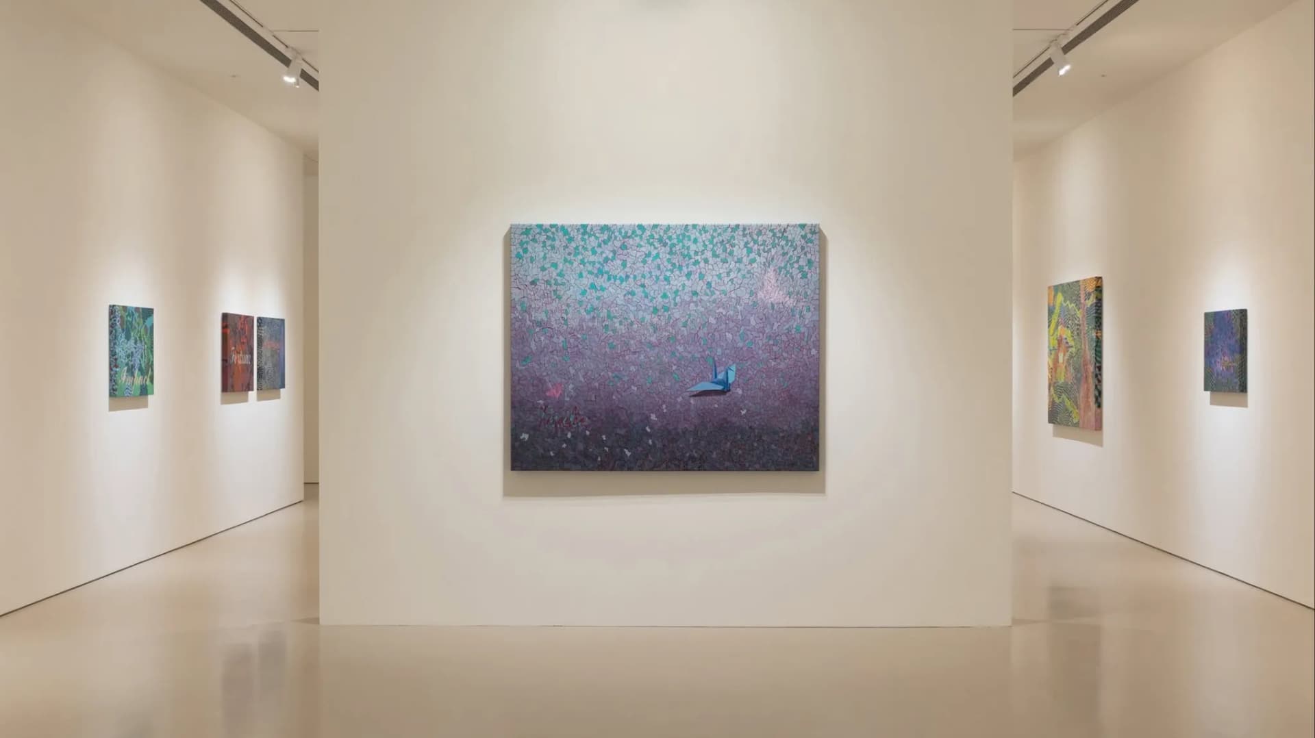 誠品畫廊內王玫玲個展「關鍵字—延續」的展場實景。明亮簡約的白色展覽空間中央正牆上,掛著一幅大型油畫作品,畫中以紫綠色調的幾何網格與點陣風格呈現,中央繪有一隻藍色紙鶴與蝴蝶造型;左右兩側延伸的展覽牆面上則間隔陳列著多幅色彩鮮豔、帶有網格與關鍵字元素的藝術畫作。