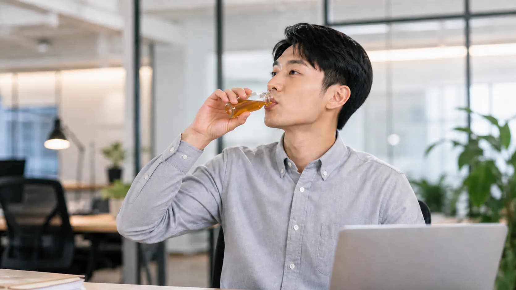 上班族坐在辦公室筆電前飲用小瓶液態飲,呈現葉黃素液態飲隨開即飲的補充情境。