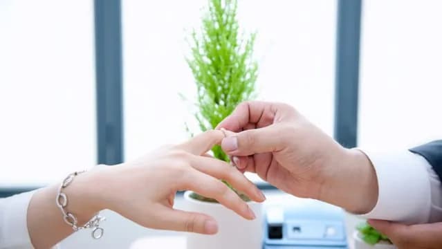 新人在室內交換戒指,男方正將戒指戴到女方手指上。