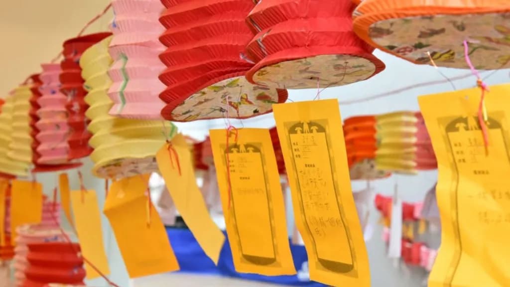 中秋節燈謎活動現場,紅、粉及橙色燈籠下掛滿黃色燈謎卡,供民眾猜謎同樂。