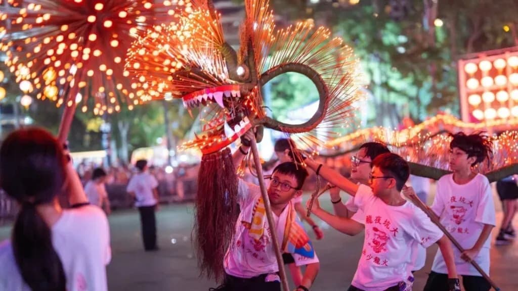 香港大坑舞火龍中秋慶典中,大坑少年火龍隊青少年身穿白色 T 恤舉起插滿香枝的發光火龍。